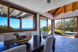 Un comedor con mesa y sillas y ventanas. en Villa Malaya con 2 piscine per 18 persone, en Alghero