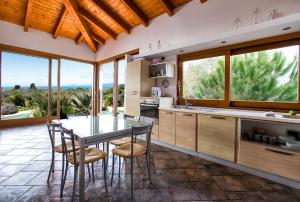 Una cocina con mesa y sillas y ventanas. en Villa Malaya con 2 piscine per 18 persone, en Alghero