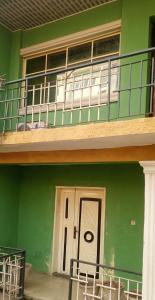 ein grünes Gebäude mit einem Balkon und einer weißen Tür in der Unterkunft Greendale apartment and Lodge in Ibadan