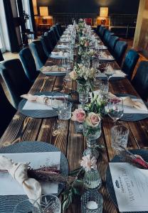 una larga mesa de madera con vasos y flores. en Piesteritzer Hof - Hotel Garni en Lutherstadt Wittenberg