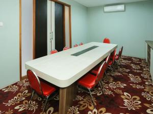 Super OYO Townhouse OAK Hotel Fiducia Pondok Gede في جاكرتا: قاعة اجتماعات مع طاولة بيضاء وكراسي حمراء