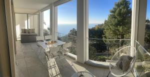 einen Balkon mit 2 Stühlen und einem großen Fenster in der Unterkunft Appartement de luxe Eze village vue mer avec piscine in Èze