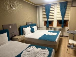 a bedroom with two beds and a window with blue curtains at MEVLANA ŞEMS HOTEL in Konya +149 photos