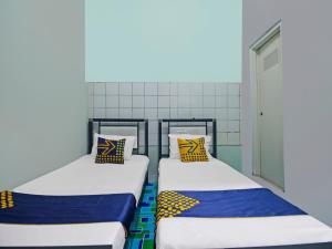 2 Betten nebeneinander in einem Zimmer in der Unterkunft SPOT ON 92219 Pondok Karisma Syariah in Tasikmalaya