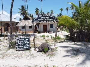 a restaurant on the beach with a sign in the sand at Stonefish Inn Jambiani in Jambiani