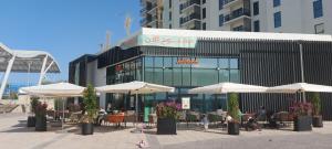 een restaurant met witte parasols voor een gebouw bij Deluxe Apartment on YAS with Sea View Balcony in Abu Dhabi