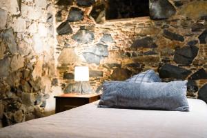 a bedroom with a stone wall with a bed and a lamp at Archontiko Rousias in Nicosia