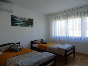 two twin beds in a room with a window at Apartman Dabrović in Novska