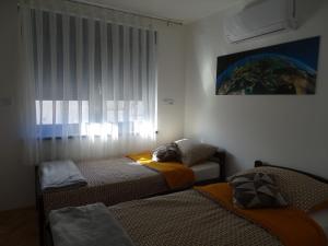 a bedroom with two beds and a window at Apartman Dabrović in Novska