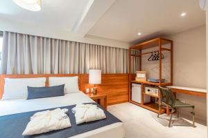 a bedroom with a bed and a desk and a chair at MAIHAI Porto in Porto De Galinhas