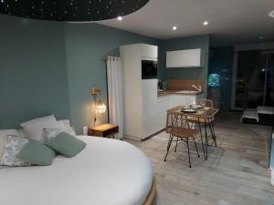 1 dormitorio con cama, mesa y cocina en Au Spa d'eau pâle, en Ferques