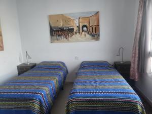 two beds in a room with a painting on the wall at Villa Acoran in Costa Teguise