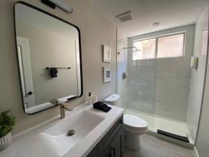 uma casa de banho com um lavatório, um chuveiro e um espelho. em Desert LUXURY! 6 bdrm, 3 bath & HEATED pool (SLEEPS 16) em Chandler