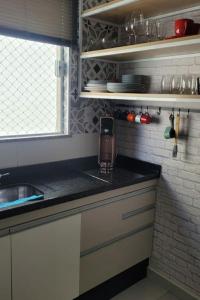 a kitchen with a counter with a cell phone on it at Apto 1o andar novo 2 Dorm - próximo ao centro in Poços de Caldas