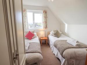 two beds in a small room with a window at Crag View in Underbarrow