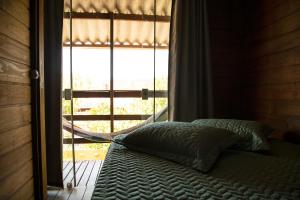 1 cama frente a una ventana en una habitación en Chalé Namastê Pinheira 1, en Palhoça
