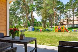 a patio with a table and a park with a playground at Holiday homes with fireplaces, Jaroslawiec in Jarosławiec