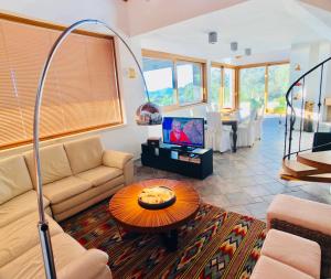 Una sala de estar con un sofá y un televisor. en Villa Malaya con 2 piscine per 18 persone, en Alghero