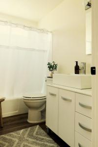 Baño blanco con aseo y lavamanos en Cozy Family Home - 20 Mins from Disneyland en Placentia
