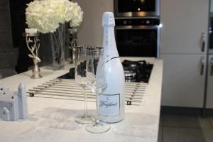 a bottle of wine and two wine glasses on a kitchen counter at Stylish 4-Bedroom House near NEC/BHX in Solihull