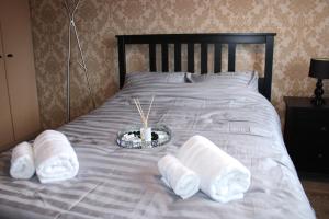 uma cama com toalhas e uma tigela de velas em Stylish 4-Bedroom House near NEC/BHX em Solihull