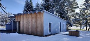 uma pequena casa com uma fachada de madeira na neve em Ferienhaus im Wesenitztal em Stolpen