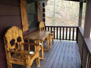 a wooden porch with two chairs and a wooden table at Dollywood-Brand New Dancing Bear 4 in Pigeon Forge