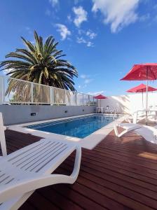 a pool with white chairs and a palm tree on a building at Catalina Hotel in Colón