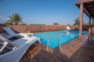 een zwembad met een terras en stoelen op een houten terras bij סוויטות פנינת המעיינות in Reẖov