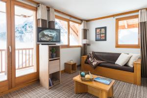 ein Wohnzimmer mit einem Sofa und einem TV in der Unterkunft Lagrange Vacances Les Balcons des Aiguilles in La Toussuire