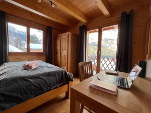 um quarto com uma cama e uma secretária com um computador portátil em Chalet familial em Chamoson