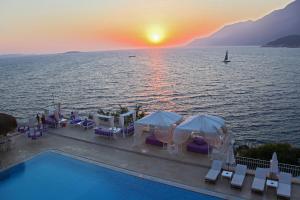 a pool with tables and chairs and a boat in the water at Lukka Exclusive Hotel – Adult Only +12 in Kaş