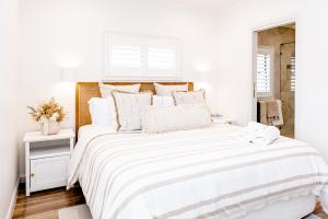 um quarto branco com uma cama grande e lençóis brancos em The Lookout em Bargara