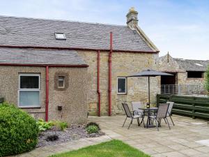 a patio with a table and chairs and an umbrella at The End Hoose in Whitsome