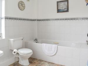 a white bathroom with a toilet and a bath tub at The End Hoose in Whitsome