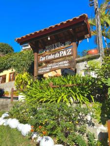 Pousada Cantinho da Paz في إيتاتيايا: علامة في حديقة بها نباتات وزهور