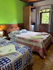 Pousada Cantinho da Paz في إيتاتيايا: سريرين في غرفة بجدران خضراء
