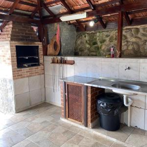 uma cozinha com um lavatório e uma parede de tijolos em Pousada Cantinho da Paz em Itatiaia