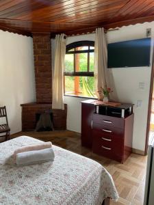 a bedroom with a bed and a dresser and a window at Pousada Cantinho da Paz in Itatiaia