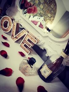 a bottle of wine and roses on a table with a mirror at Gesualdo da Venosa in Venosa