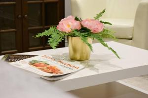 a vase with pink flowers on a table with a magazine at Home Away From Home - Basement Studio Apartment in Toronto