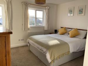 a bedroom with a bed with yellow pillows and two windows at Newly Renovated 2 Bed house nr Fistral Beach & Gannel Estuary in Newquay