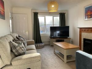 a living room with a couch and a television at Newly Renovated 2 Bed house nr Fistral Beach & Gannel Estuary in Newquay