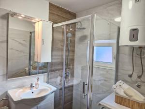 a white bathroom with a shower and a sink at Apartments Duje in Split