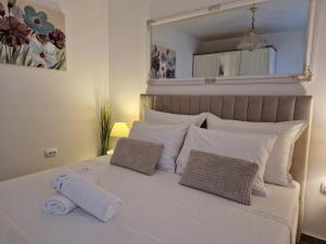 1 cama blanca con 2 almohadas y espejo en Apartments Duje, en Split