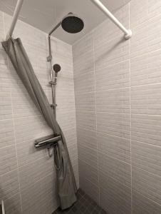 e bagno con doccia e pareti in piastrelle bianche. di Linkuva Manor Apartment a Kaunas