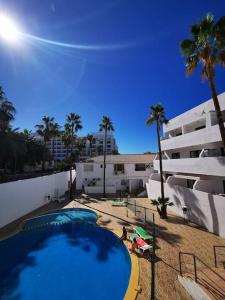 a swimming pool next to a building with palm trees at Las Americas studio in Playa de las Americas
