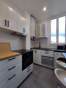 eine Küche mit weißen Schränken und einem schwarzen Geschirrspüler in der Unterkunft La vie en blanc et noir Maisons-Laffitte in Maisons-Laffitte