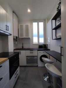 eine weiße Küche mit einer Spüle und einem Geschirrspüler in der Unterkunft La vie en blanc et noir Maisons-Laffitte in Maisons-Laffitte