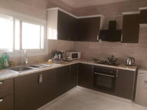 a kitchen with black cabinets and a sink and a refrigerator at Muhammed Ceesay Villa in Old Yundum